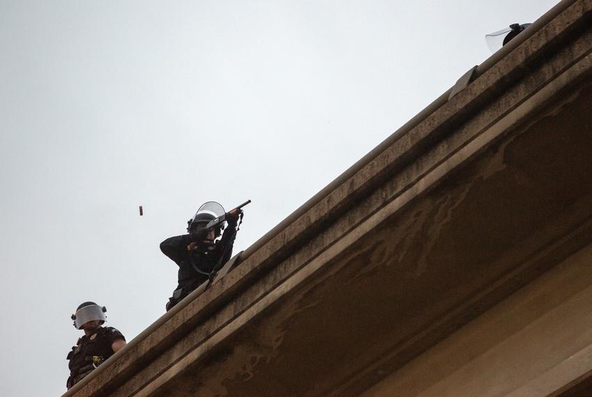 An Austin Police officer fires his weapon into a crowd of protestors from Interstate 35, near the Austin Police headquarters on May 31, 2020.